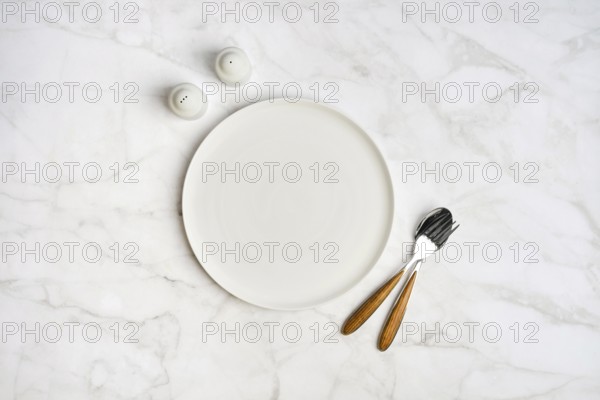 A simple dining arrangement showcases an empty white plate accompanied by a fork and knife with