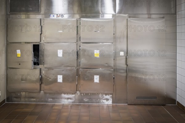 Hospital, morgue, pathology, cold room with metal doors and sterile-looking surroundings, tiled