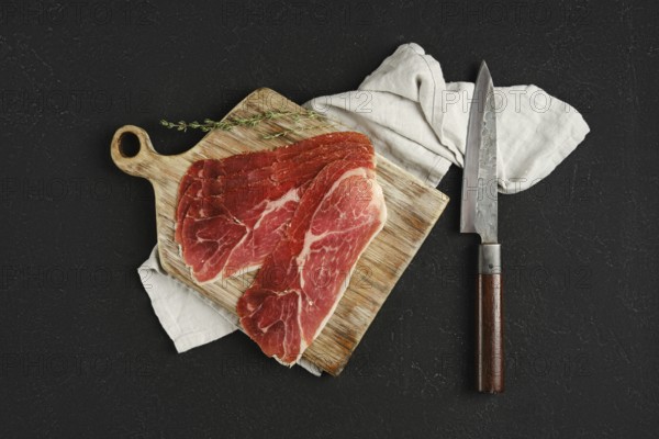 Overhead view of jamon iberico cured pork meat on a wooden cutting board, accompanied by a sharp