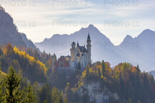 Romantic castle enthroned in autumnal forests against a mountain backdrop, Neuschwanstein,