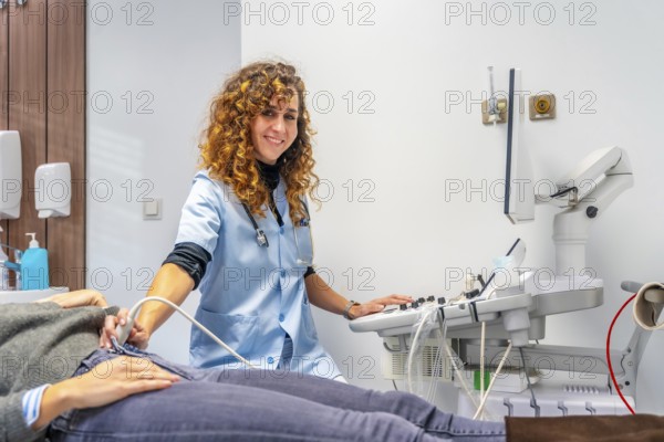 Female doctor smiling at camera while performing an ultrasound to a pregnant woman into the
