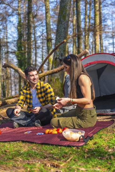 Hikers enjoying a game of cards while camping in the forest, sharing laughter and creating memories