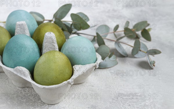 Easter colored eggs, in green and turquoise tones, with eucalyptus leaves, Easter card, top view,