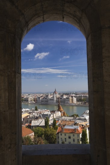 Budapest city skyline with Danube river and Hungarian parliament through stone arch in summer,