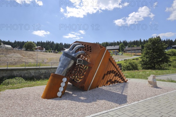 Sculpture bandoneon with hand, strap and buckle as a monument and symbol of musical instrument