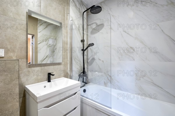 A beautifully designed bathroom showcases marble walls and a stylish shower-bathtub combo. A modern