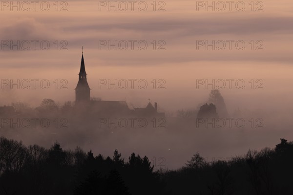 Wisps of mist drift into the town of Kronberg im Taunus in the morning shortly in front of sunrise.