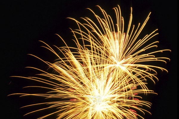 New Year's Eve fireworks, vivid fireworks in the night sky with golden, yellow stripes of light and