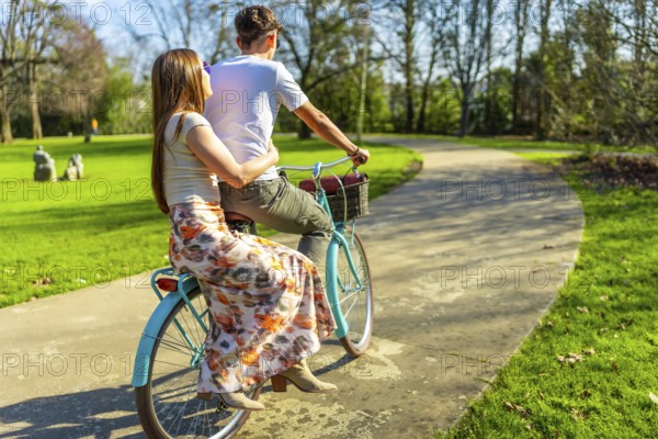 Romantic couple enjoying a leisurely bike ride through a sunny park, embracing the simple joys of