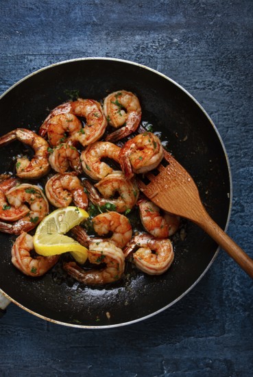 Fried tiger prawns, jumbo, in garlic sauce, in butter, with herbs, in a frying pan, homemade, no