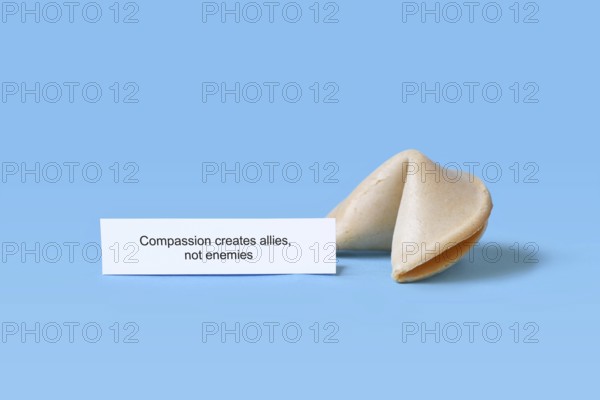 Fortune cookie with motivational text saying 'Compassion creates allies, not enemies on blue