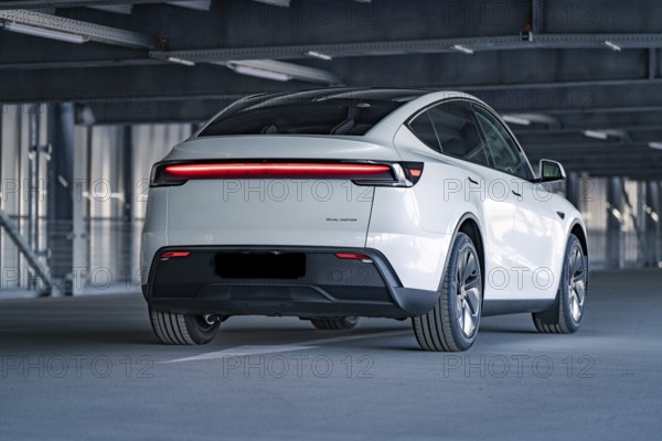 Rear of a modern electric car with eye-catching LED strip in a multi-storey car park, Tesla New