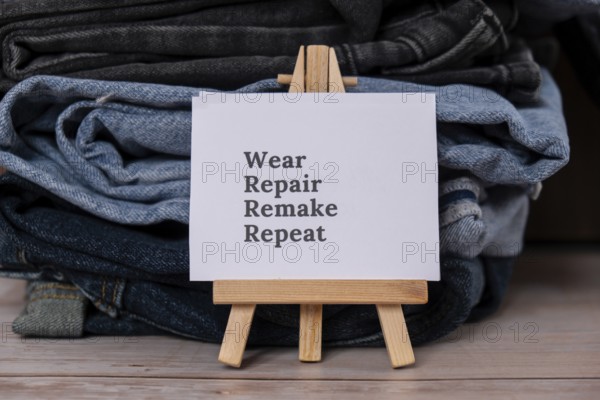 WEAR REPAIR REMAKE REPEAT text on paper note on Jeans clothes assortment Second hand sustainable