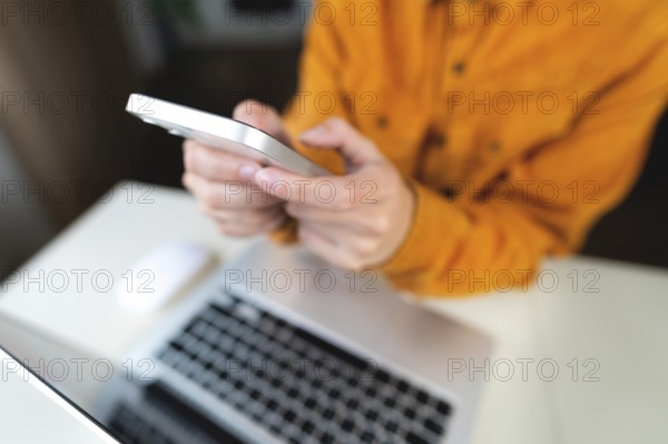 Female student's hands with a phone on the background of a modern laptop and desktop. Freenacer