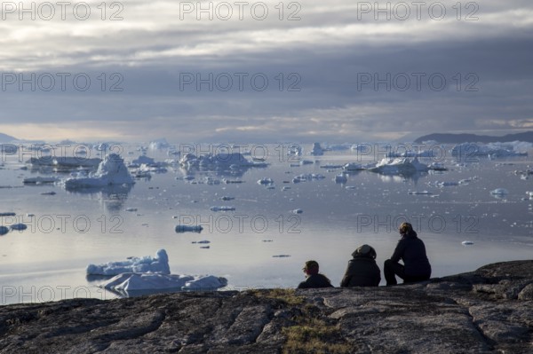 Rodebay, Greenland, July 09, 2018: A group of people sitting and looking at icebergs. Rodebay, also