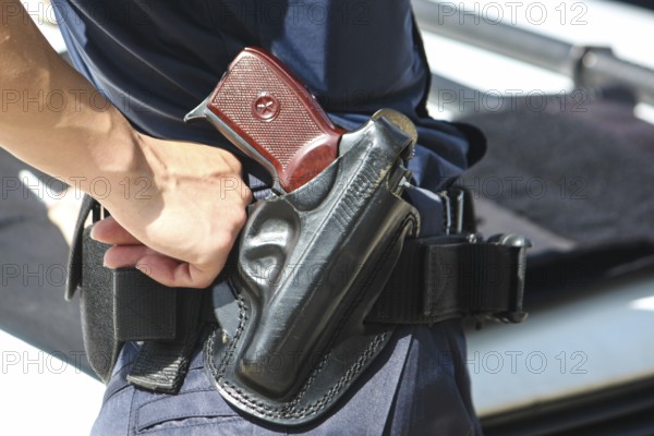A woman's hand touches a body and a gun. Woman with a gun. Woman policemen with gun in a black
