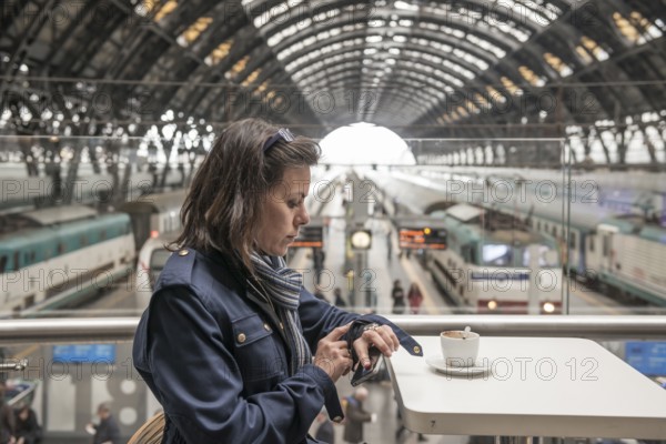 Woman in a Restaurant Drinking Coffee and Looking at Her Watch in Railroad Station in Milan,