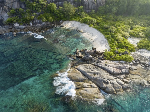 Coastline with waves, large rocks and tropical vegetation on turquoise water, aerial view,