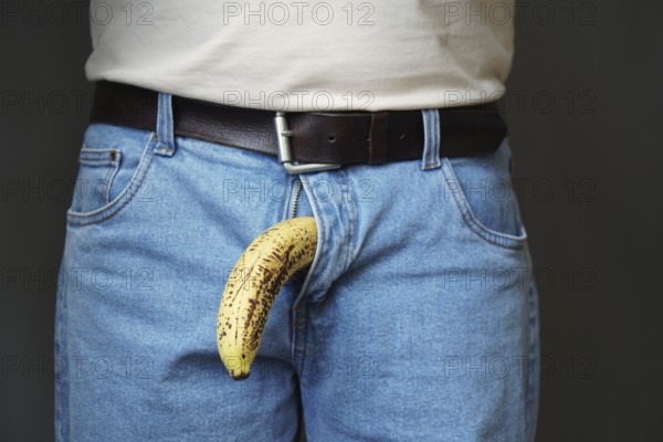 old limp drooping banana hanging from genital area of clothed unrecognizable man, impotence