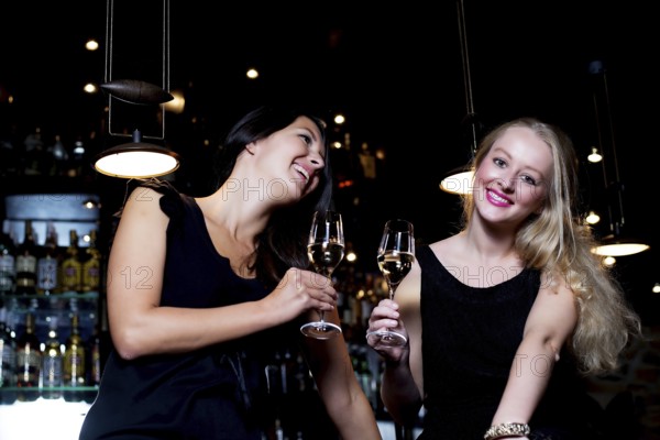 Two beautiful young women sharing their friendship and celebrating with champagne, in a fancy