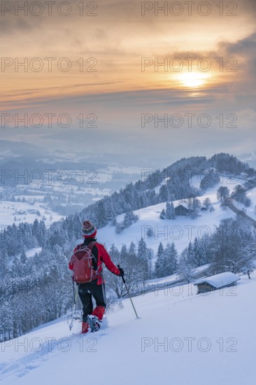 Pretty active senior woman snowshoeing in the Allgäu Alps near Oberstaufen with a view of the