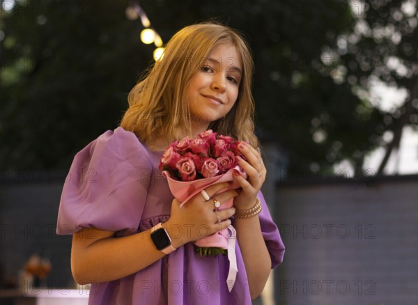 Cute teen girl with rose flowers. Child playing in summer garden. Kids gardening. Children play