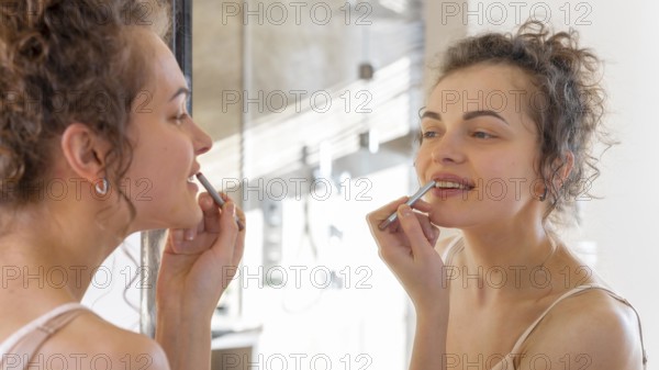 Woman looking mirror applying lipstick 2