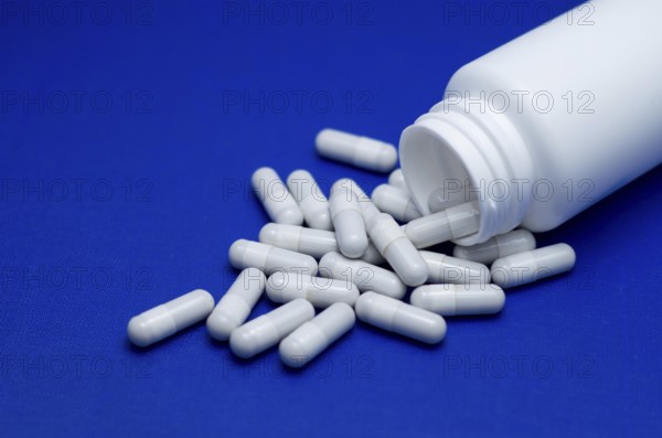 Large white pills fell from a large white bottle. Life without drugs and dependence on capsules of