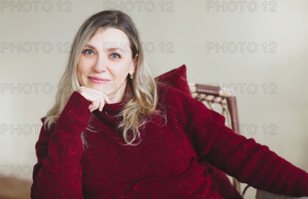 Attractive middle aged happy woman sitting and relaxing on comfortable chair at home on weekend,