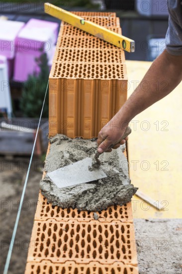 Anonymous construction worker on a building site erecting a brick wall. Brick wall of a solid house