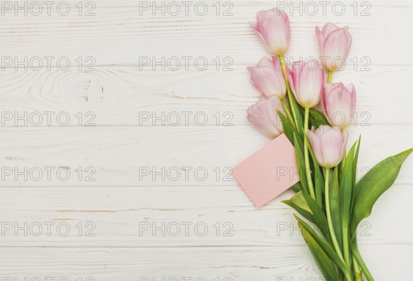 Tulip bouquet with empty card wooden table. High resolution photo