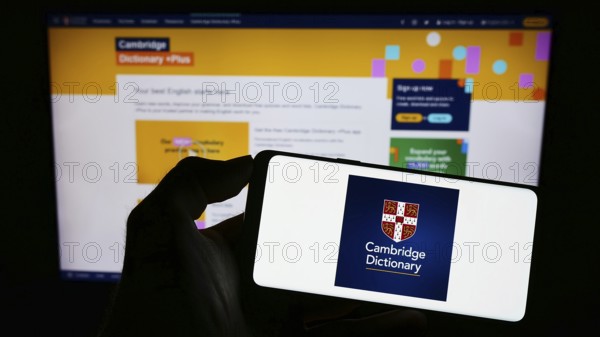Stuttgart, Germany, 07-11-2023: Person holding cellphone with logo of Cambridge Dictionary on