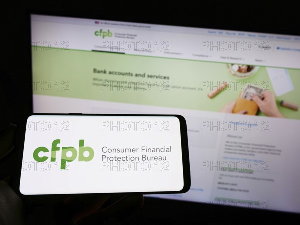 Stuttgart, Germany, 09-18-2022: Person holding mobile phone with logo of US Consumer Financial