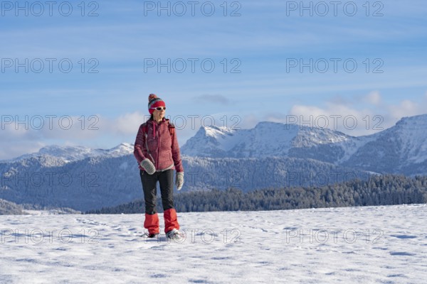 Pretty active senior woman snowshoeing in the Allgäu Alps near Oberstaufen with a view of the