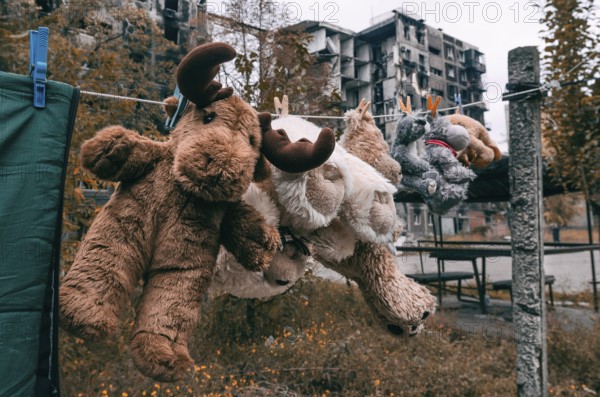 Soft toys are dried after washing against the background of a burnt-out multi-storey building in
