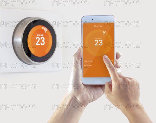 Smart Thermostat and a person setting up the temperature smart device hand hold on a white