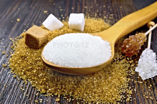 Sugar white and brown in cubes, crystal on a stick and granulated in a spoon on a wooden plank