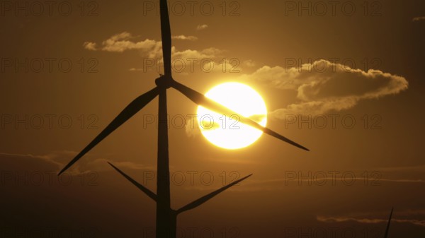 Beautiful sunrise dawn landscape with windmills or wind turbine on wind farm in rotation to