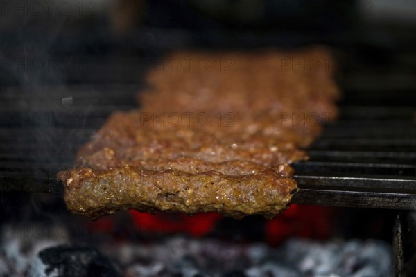 Making Spicy seekh kebabs are being grilled on burning charcoal in barbeque at a dinner party at