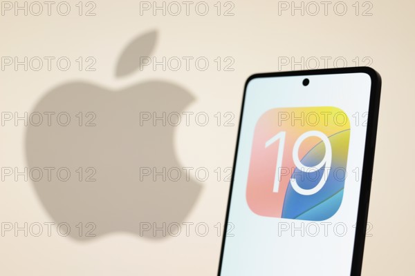 In this photo illustration, the iOS 19 logo seen displayed on a smartphone with an Apple logo in