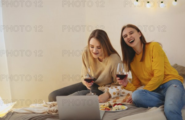 Two cute happy funny women friends having fun together, arranging home cinema evening, watching