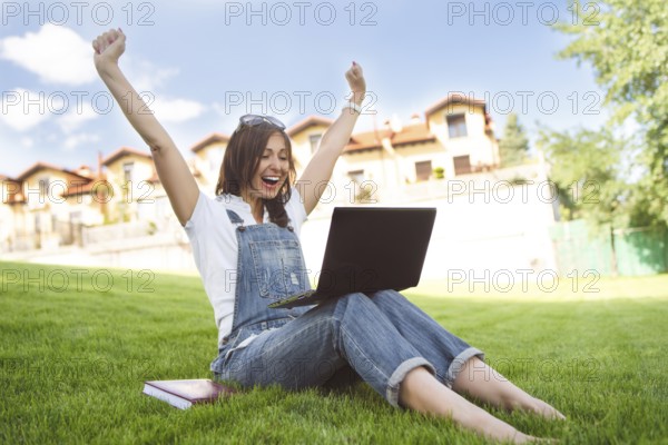 Female gets joyful emotions by talking to her friends on a conference call from notebook, she