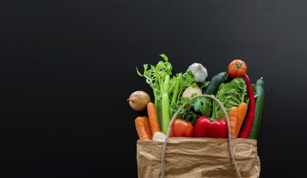 top view of fresh organic vegetables bought on weekly market in brown paper bag against dark table
