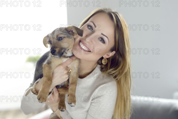 Pretty happy young woman with her pet dog held up to her cheek in her hands in a natural tender