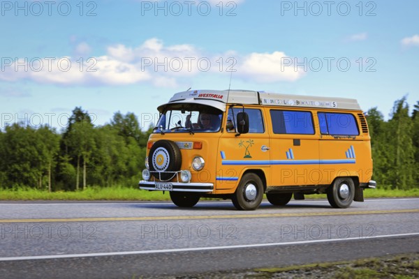 Classic yellow Volkswagen Westfalia camper van at speed on Highway 2 on a beautiful day of summer.