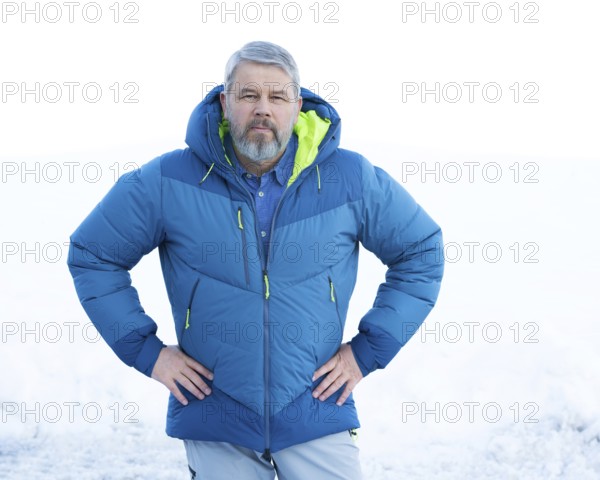 Man, 56 years old with grey hair and a full grey beard standing in front of a snowy area in winter,