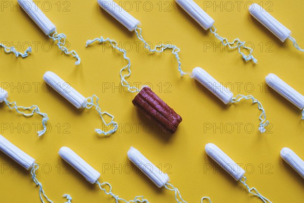 many new clean tampons and one used bloody tampon - period or menstruation flat lay concept with