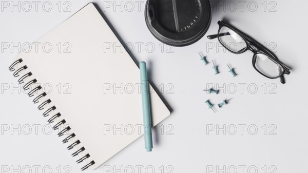 Blank spiral notepad pen coffee cup eyeglasses pushpins white background. Resolution and high