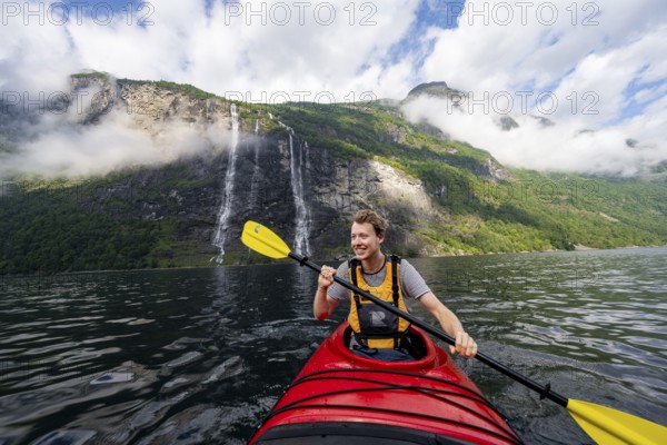 Kayak trip on the Geirangerfjord at the waterfall The Seven Sisters, Young man paddling in a kayak,