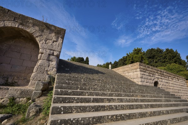 Stone staircase with ancient structures, surrounded by trees and clouds, open staircase to the